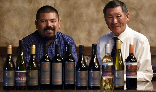 Martin Fujishin (left) and Barry Fujishin smile behind a row of wines from Fujishin Family Cellars.