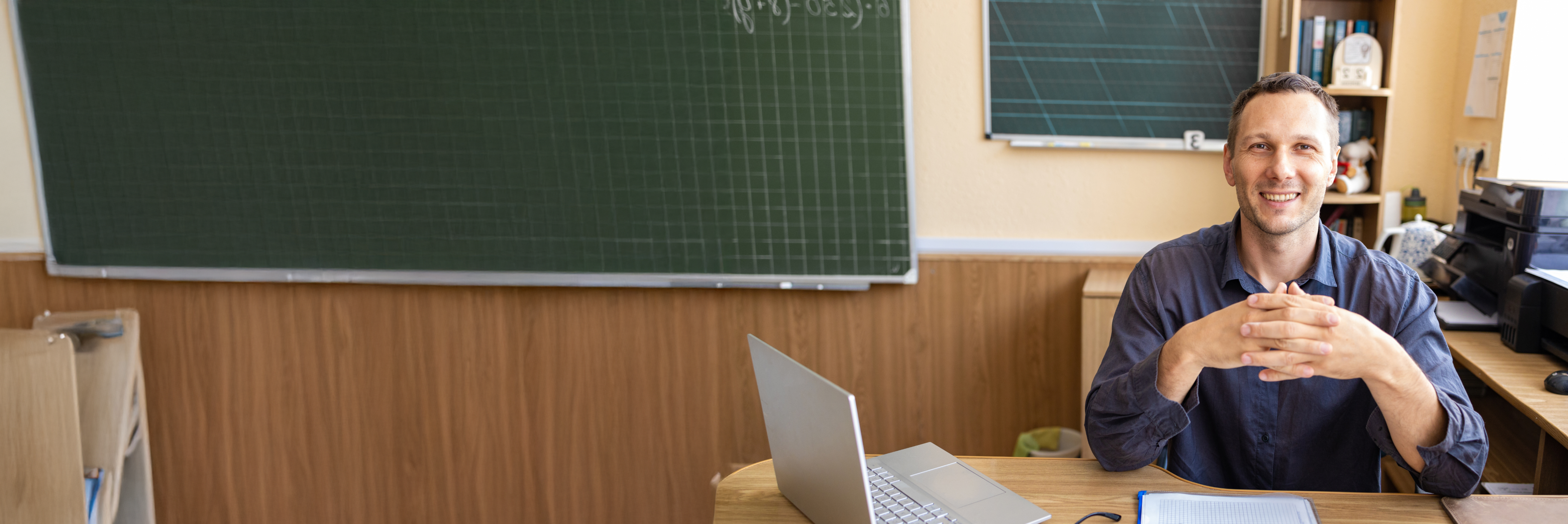 Male teacher at his classroom desk. 