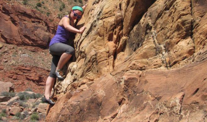 Young woman climbs outdoor rock face