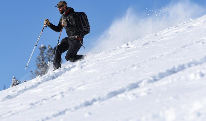 Young man skis down powdery slope