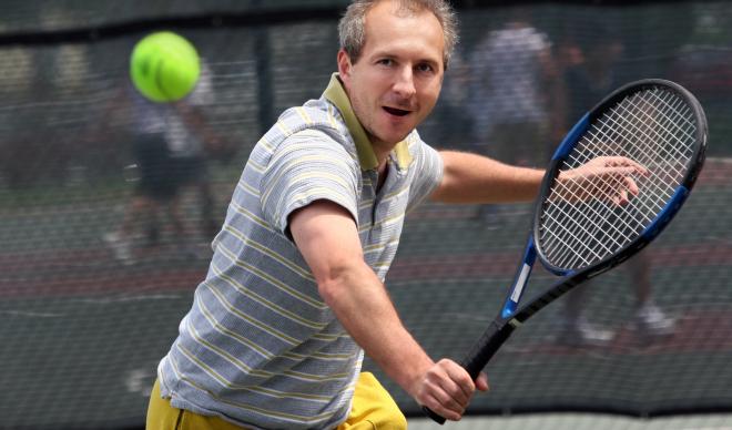 A man prepares a one-handed backhand shot in a tennis match.