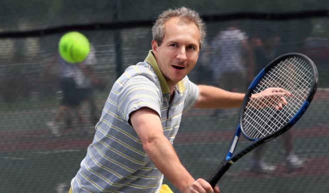 A man prepares a one-handed backhand shot in a tennis match.