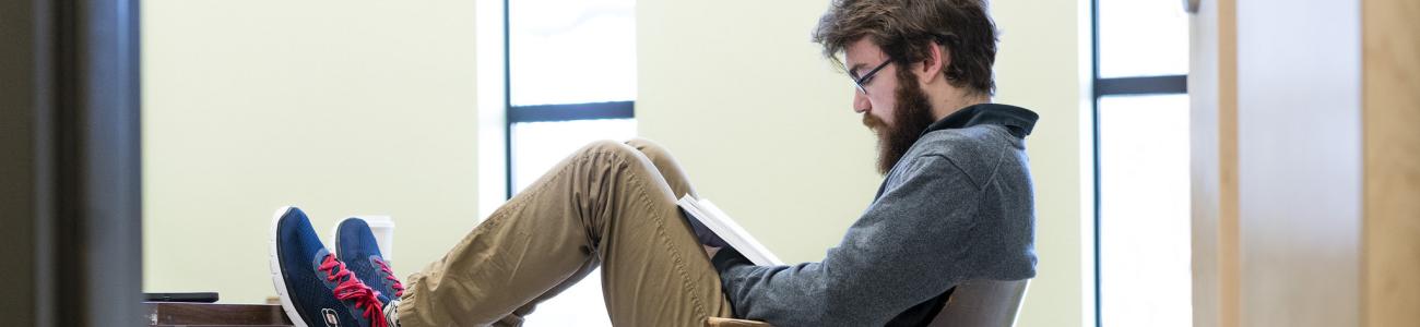 Student casually reading in a chair